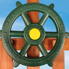 A green ship wheel on a wooden deck.