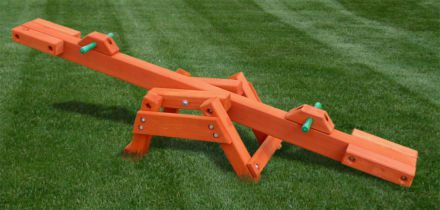 A wooden saw is sitting on a grassy field.