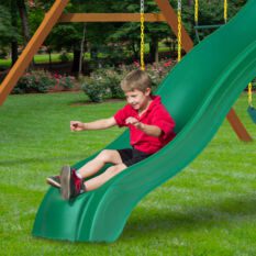 A boy is playing on a green slide.