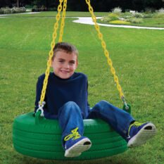 A young boy sitting on a Chateau w/ Tire Swing, Ramp Swing Set.
