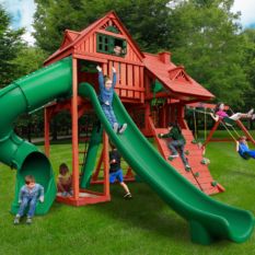 A green slide and Dane’s Den Deluxe Swing Set in a grassy area.