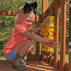 A little girl playing on a Treasure Trove II Swing Set.