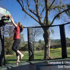 A girl jumping on a Power Double Bounce Trampoline with a basketball hoop.