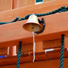 A Dinner Bell hanging from a wooden fence.