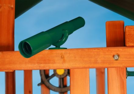 A green Play Telescope sits on top of a wooden play structure.