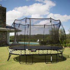 A SpringFree Large Oval Smart Trampoline in the backyard of a house.