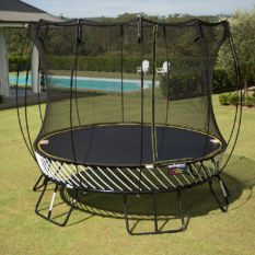 A SpringFree Medium Round Smart Trampoline in a backyard with a net.