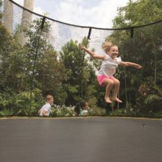 A little girl jumping on a SpringFree Large Square Smart Trampoline.