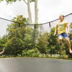 Two children jumping on a SpringFree Jumbo Square Smart Trampoline.