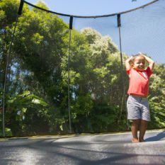 A young boy standing on a SpringFree Medium Round Smart Trampoline.