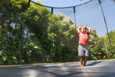 A young boy standing on a SpringFree Medium Round Smart Trampoline.