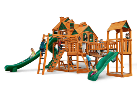 Kids playing on wooden playground with green slides, ladders, and a bridge