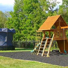 A backyard playground with a slide and swings is sold by the ton of Rubber Mulch.