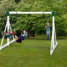 Two children swinging on a Free Standing Swings System in a yard.