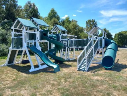 A VinylNation Lucky Star Swing Set with green slides and swings.
