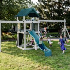 Kids playing on a VinylNation The Orlando Deluxe Swing Set in a backyard.